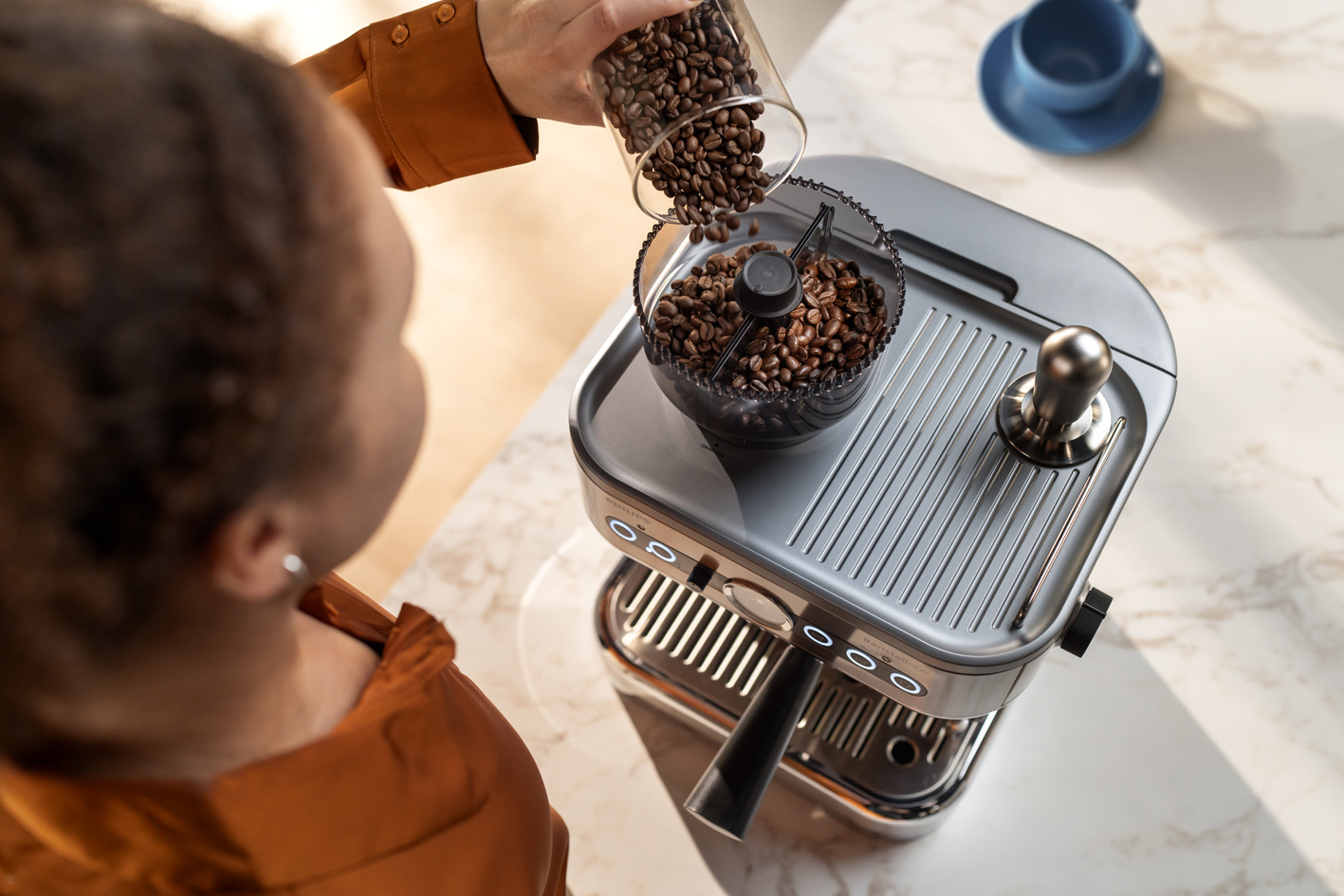 Jauna sieviete ber kafijas pupiņas Philips Barista Brew​ pupiņu tvertnē
